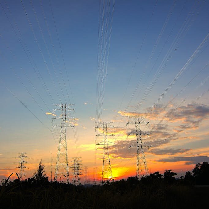 Three Black Metal Electricity Posts during Golden Hour